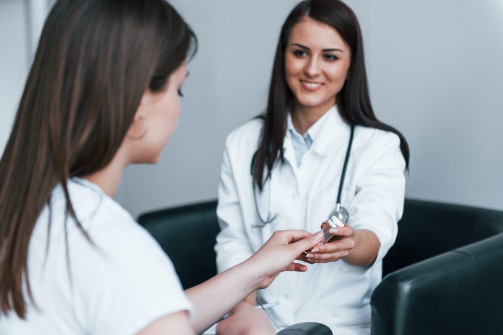 Doctor gives drugs to patient. Young woman have a visit with female doctor in modern clinic